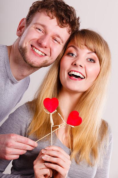 抱着小心脏棍子上两个人象征着良好的关系感情可爱的幸福的夫妇与心