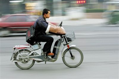 2023年12月9日,东城区幸福大街路口,一名男子在路上骑行电动自行车.