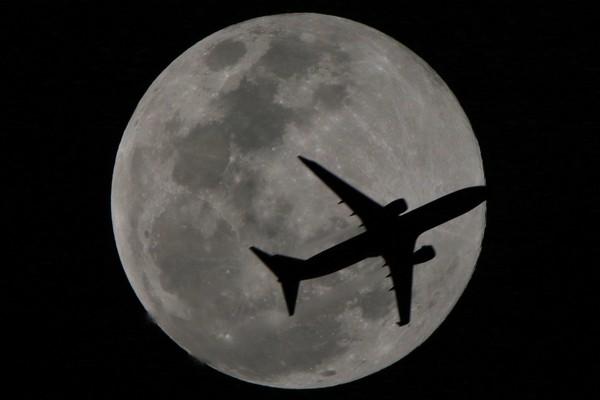飞机越过超级月亮,留下完美剪影.(图/张文良授权提供)