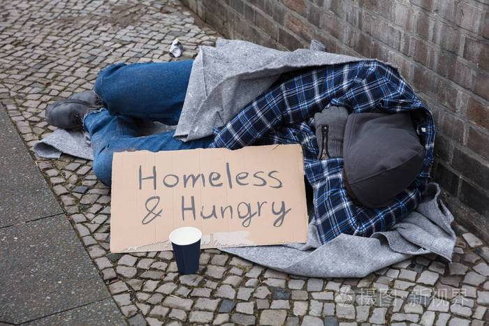 男乞丐躺在街上无家可归和饥饿的文本纸板