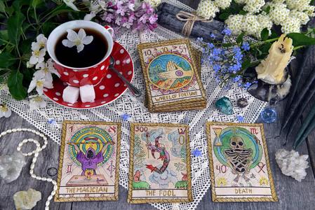 塔罗牌上有一杯茶花和木板上的黑蜡烛. 神秘的神秘和占卜仍然是生命.