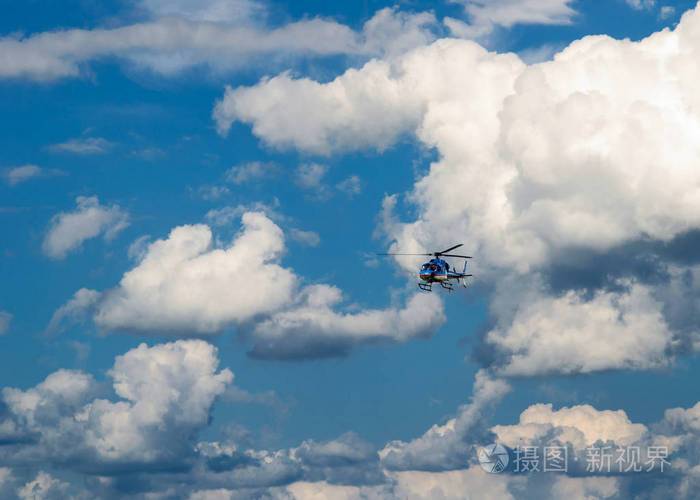 直升机在蓝色多云的天空中飞翔
